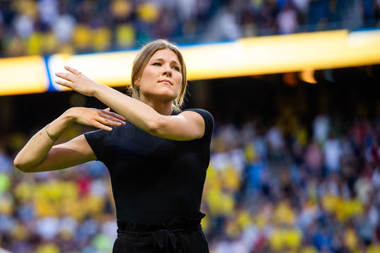 En sångerska sjunger nationalsången på teckenspråk