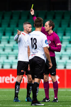 Referee Jan Morten Tennøy hands out a yellow card to