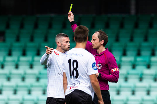 Referee Jan Morten Tennøy hands out a yellow card to