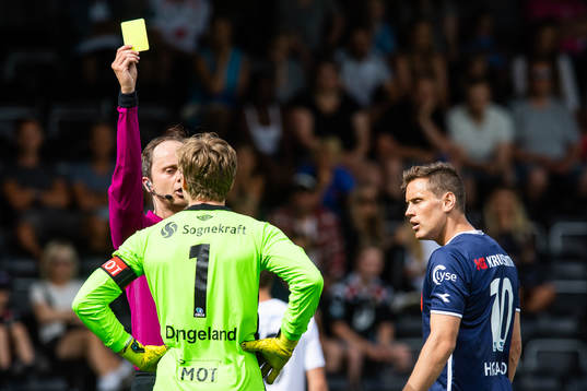 Referee Jan Morten Tennøy hands out a yellow card to