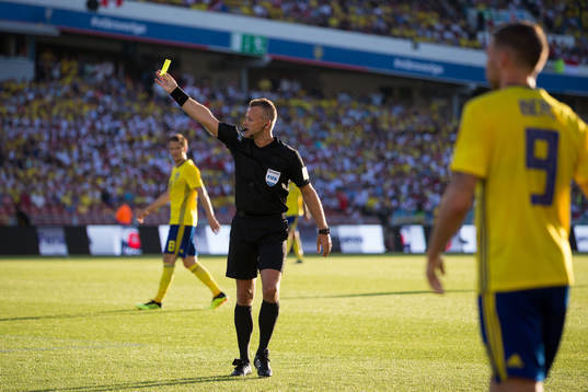 Referee  Svein Oddvar Moen showing a yellow card