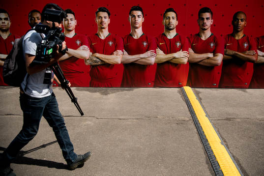 A member of the press walks by a banner with the Portuguese