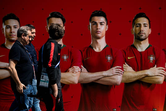 Members of the press walks by a banner with the Portuguese
