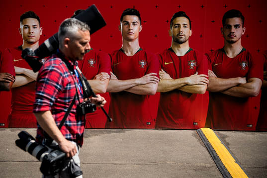 A member of the press walks by a banner with the Portuguese