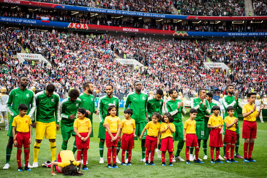 A mascot girl prays in front of the players of Saudi Arabia