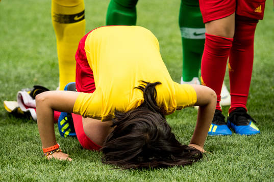 A mascot girl prays in front of the players of Saudi Arabia