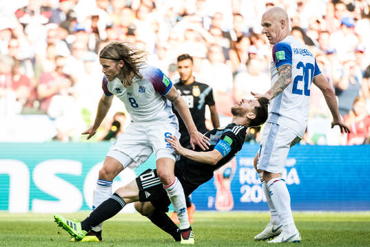 Birkir Bjarnason of Iceland stops Lionel Messi of Argentina