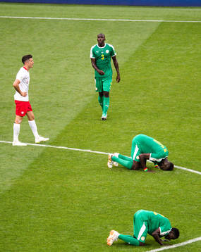 Players of Senegal celebrates while Robert Lewandowski of