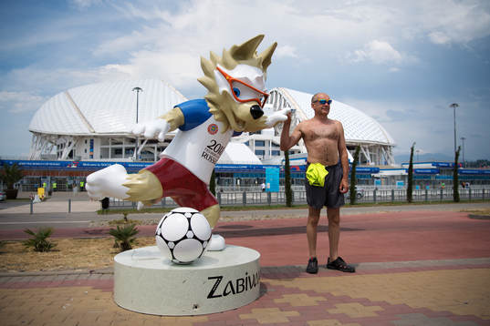 An man poses with the 2018 World Cup mascot Zabivaka in