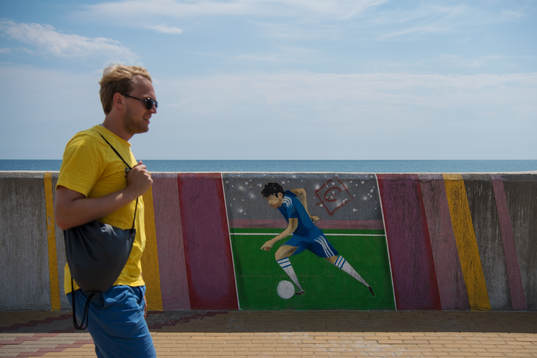 A Swedish fan passing a mural with a football player
