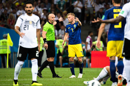 referee Szymon Marciniak  and Sebastian Larsson of Sweden