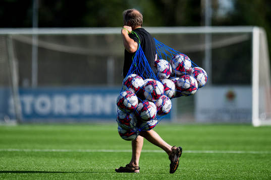 A man with footballs in a net