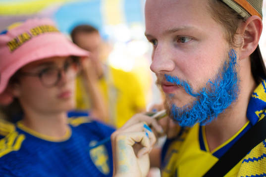 A Swedish fan get his beard painted