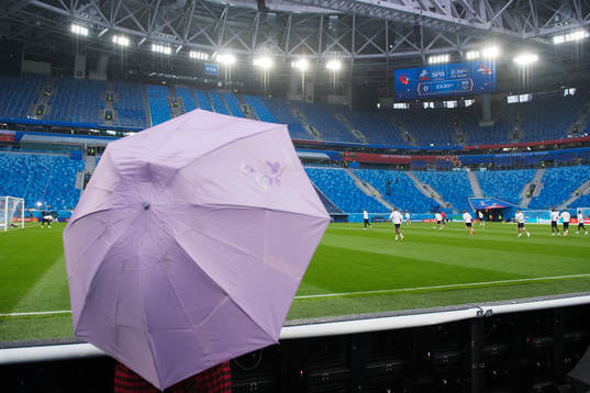 A member of the press holds an umbrella when watching the