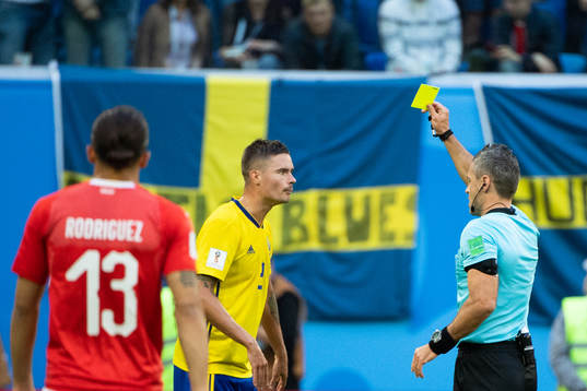 Mikael Lustig of Sweden is given a yellow card