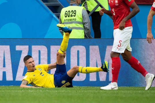 Mikael Lustig of Sweden lies down and reaches for his leg