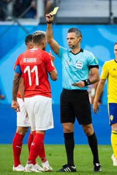 Referee Damir Skomina gives Valon Behrami a yellow card