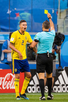 Mikael Lustig of Sweden is given a yellow card by referee