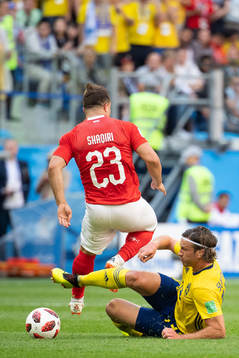 Gustav Svensson of Sweden tackles Xherdan Shaqiri of