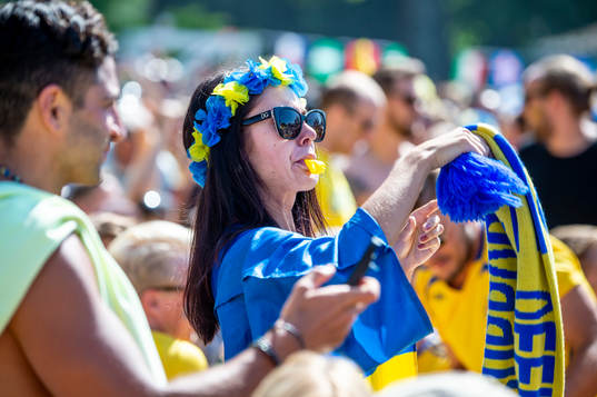 Kvinnlig supporter med visselpipa följer matchen mellan
