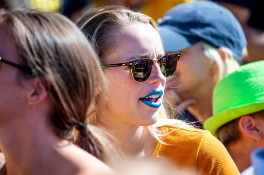 Kvinnlig supporter med blått läppstift följer matchen