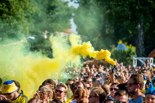 En supporter tänder en gul rökgranat innan matchen mellan