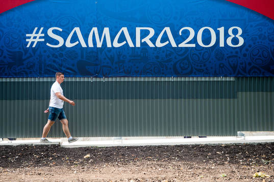 A person walks by a board with the text "#Samara2018"