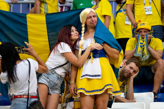 A supporter hugs a of crying Swedish supporter with a flag