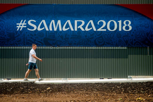 A person walks by a board with the text "#Samara2018"