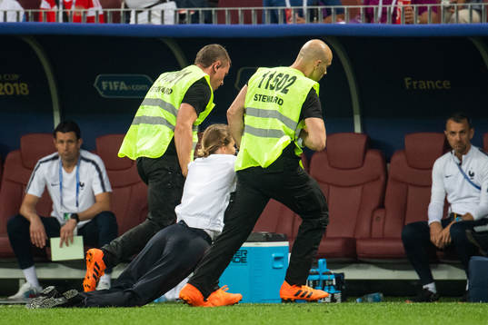 Stewards drag a pitch invader away