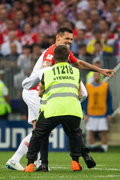 Dejan Lovren of Croatia and a steward hold a pitch invader