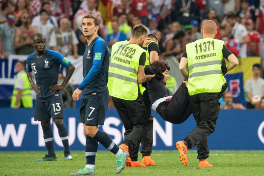 Stewards carry away a pitch invader
