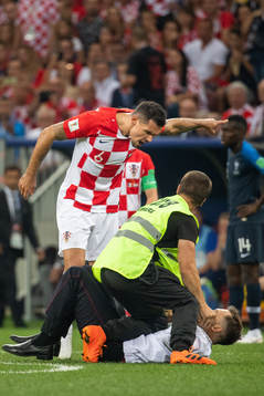 Dejan Lovren of Croatia reacts against a pitch invader who