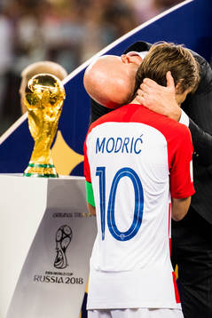 Luka Modric of Croatia walks by the trophy and gets a hug