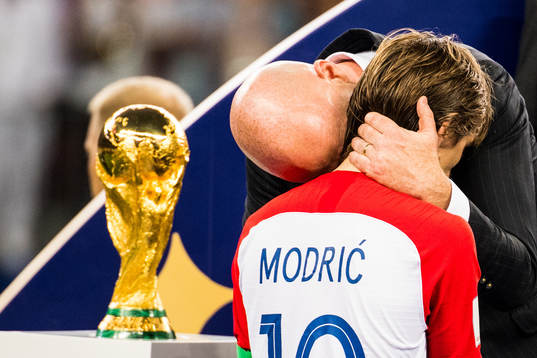 Luka Modric of Croatia walks by the trophy and gets a hug