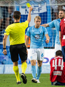Referee Matej Jug gives a yellow card to Oscar Lewicki of