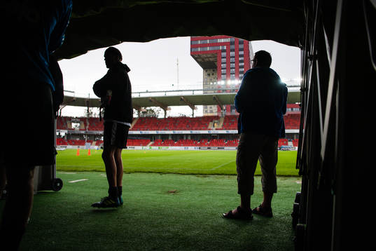 Två personer står i spelartunneln när det regnar och