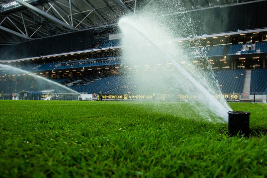 En vattenspridare på naturgräset på Friends Arena innan
