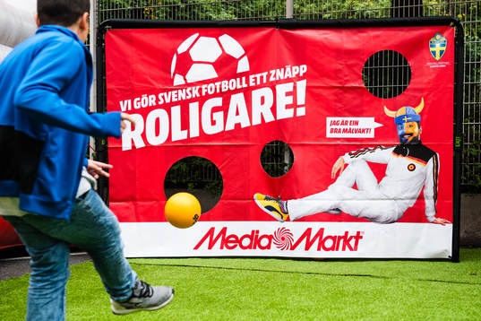 En kille skjuter boll i Media Markts monter i fnazone