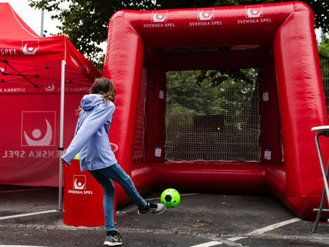 En tjej skjuter en fotboll i Svenska Spels monter i fanzone