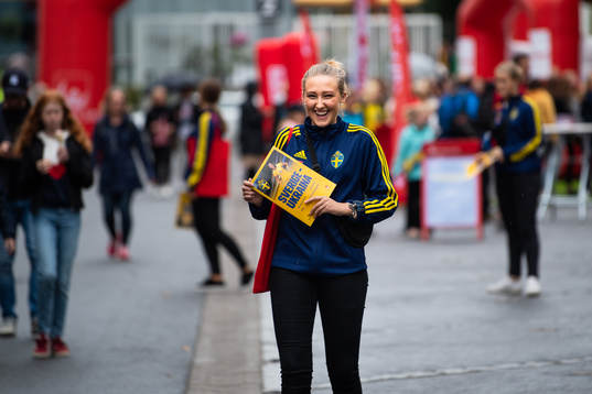 En tjej säljer matchblad i fanzone