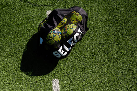 Bollar i en väska på konstgräs innan fotbollsmatchen i