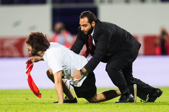 A pitch invader is wrestled by security