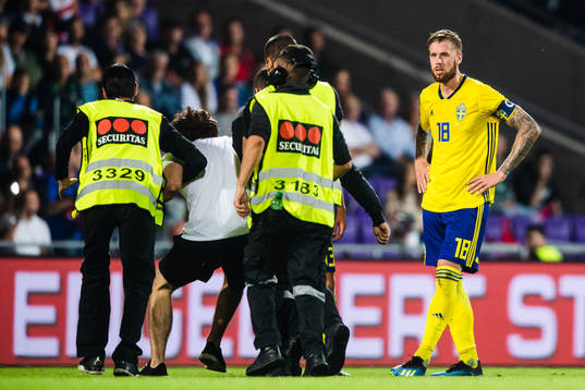Pontus Jansson of Sweden sees a pitch invader escorted by