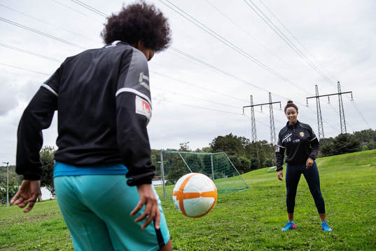 Tutu Belay och Loza Abera spelar fotboll på en gräsplätt