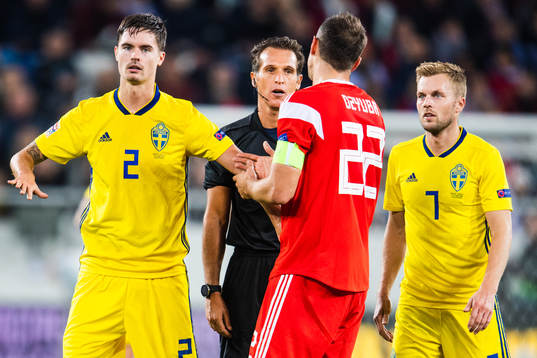 Mikael Lustig and Sebastian Larsson of Sweden with referee