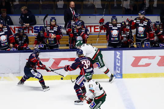 Kamp om pucken vid spelarbåsen