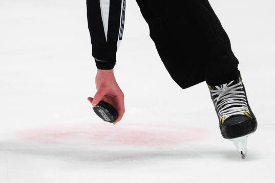 En domare plockar upp en puck