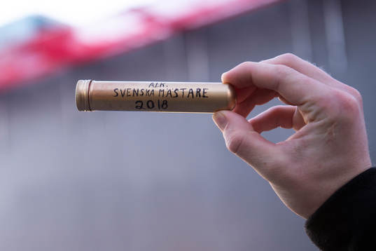 En AIK-supporter håller upp en cigarr