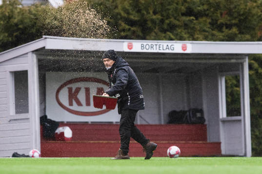 A janitor removing water from the pitch